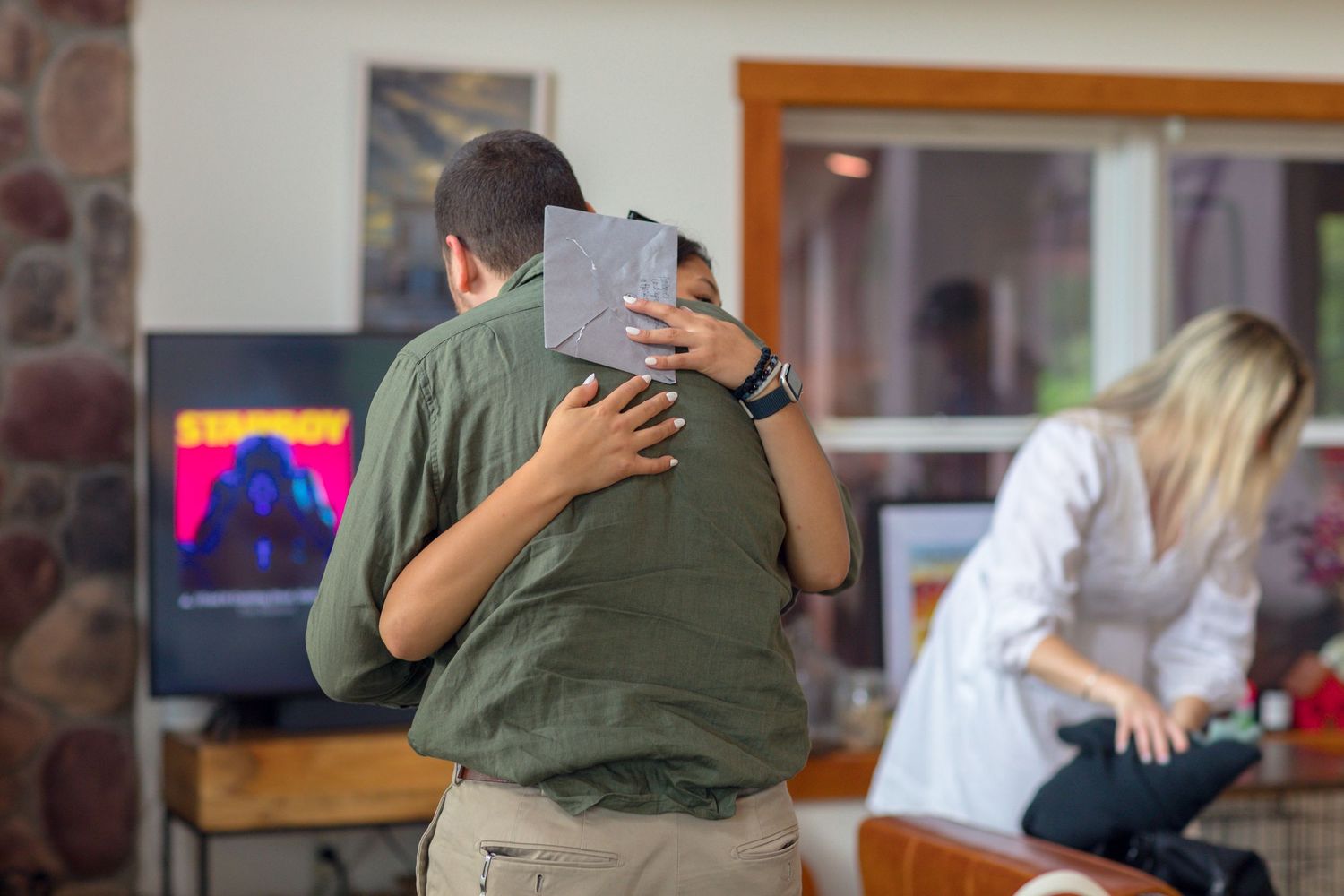 People embrace during an indoor gathering in a home setting.