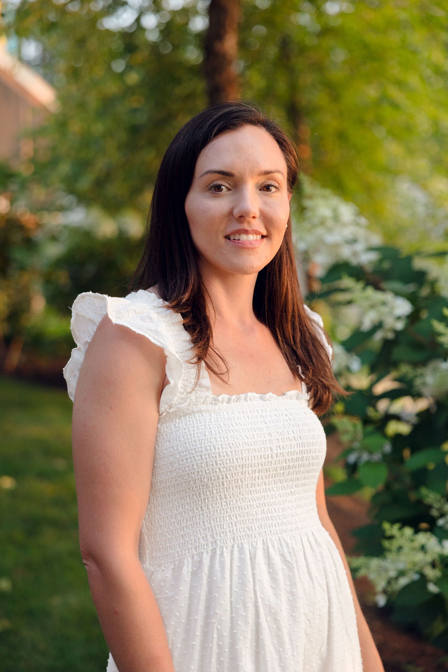 A joyful moment captured in a white summer dress against lush greenery.