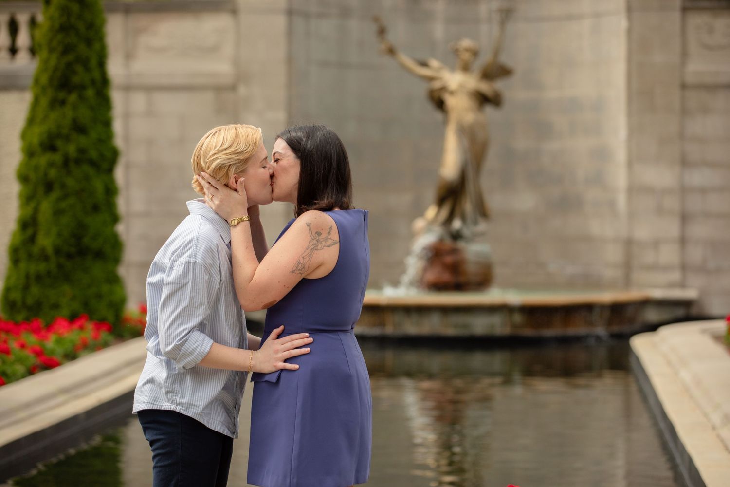 A tender embrace near an ornate fountain in a formal garden setting.