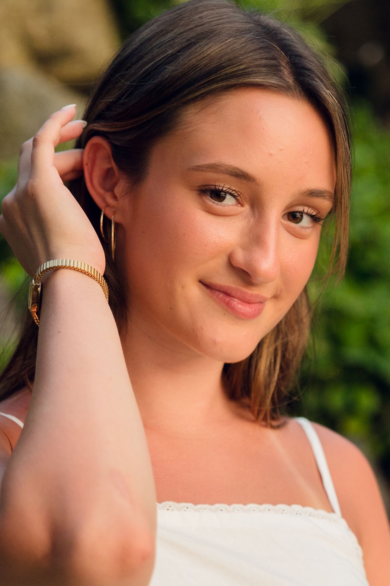 Portrait series of someone in a white top against a natural outdoor background.