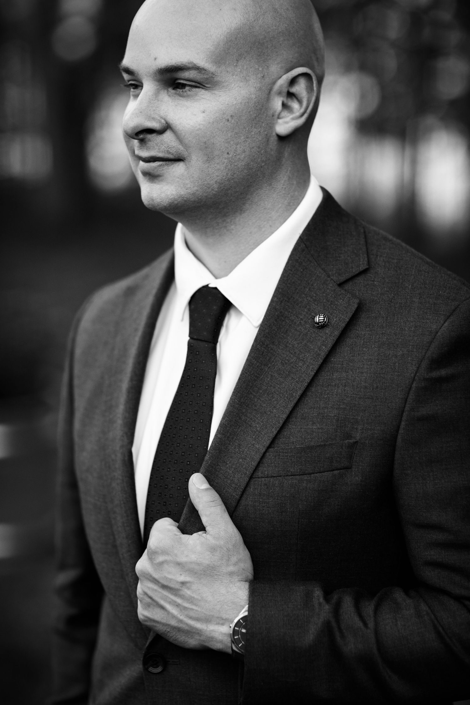 Black and white portrait sequence showing a person in a dark suit adjusting their tie in multiple poses.