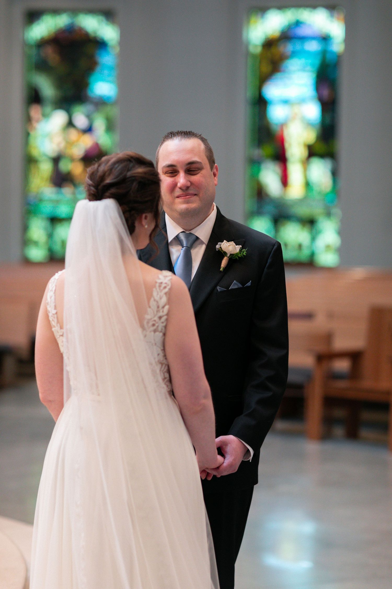 A wedding ceremony moment in a church with stained glass windows and wooden pews.