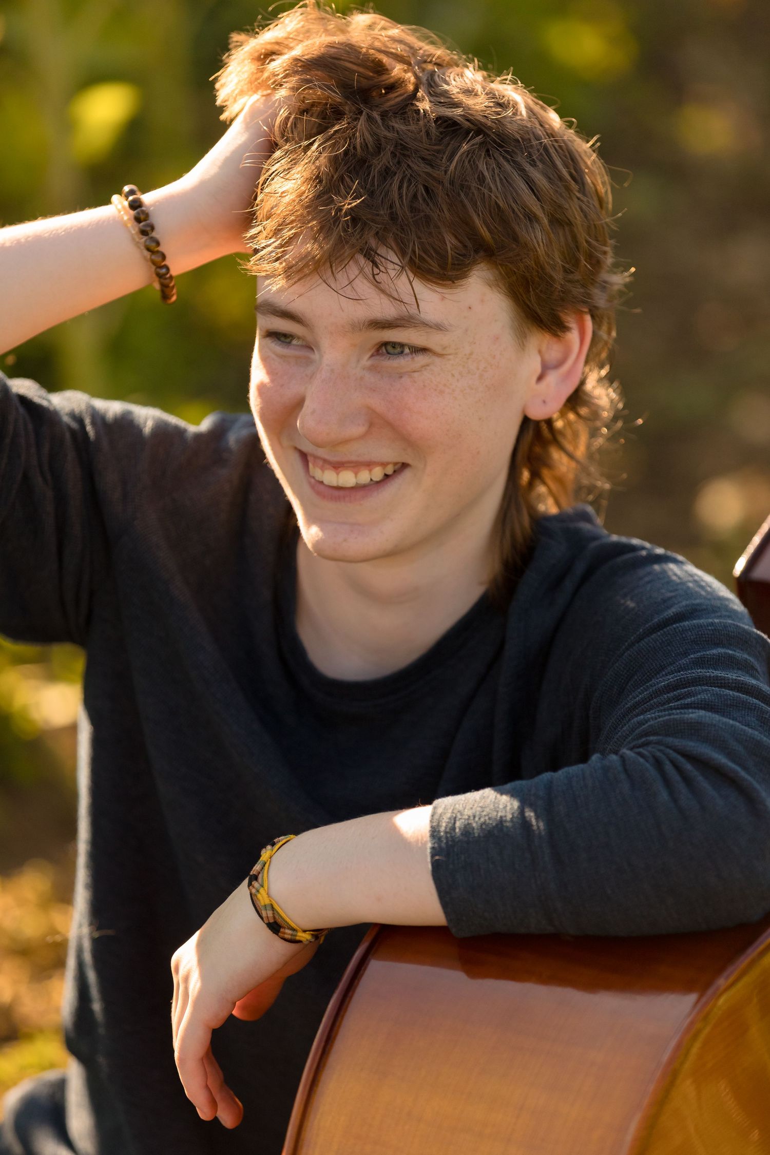 Musician with wooden instrument smiling in warm natural lighting.