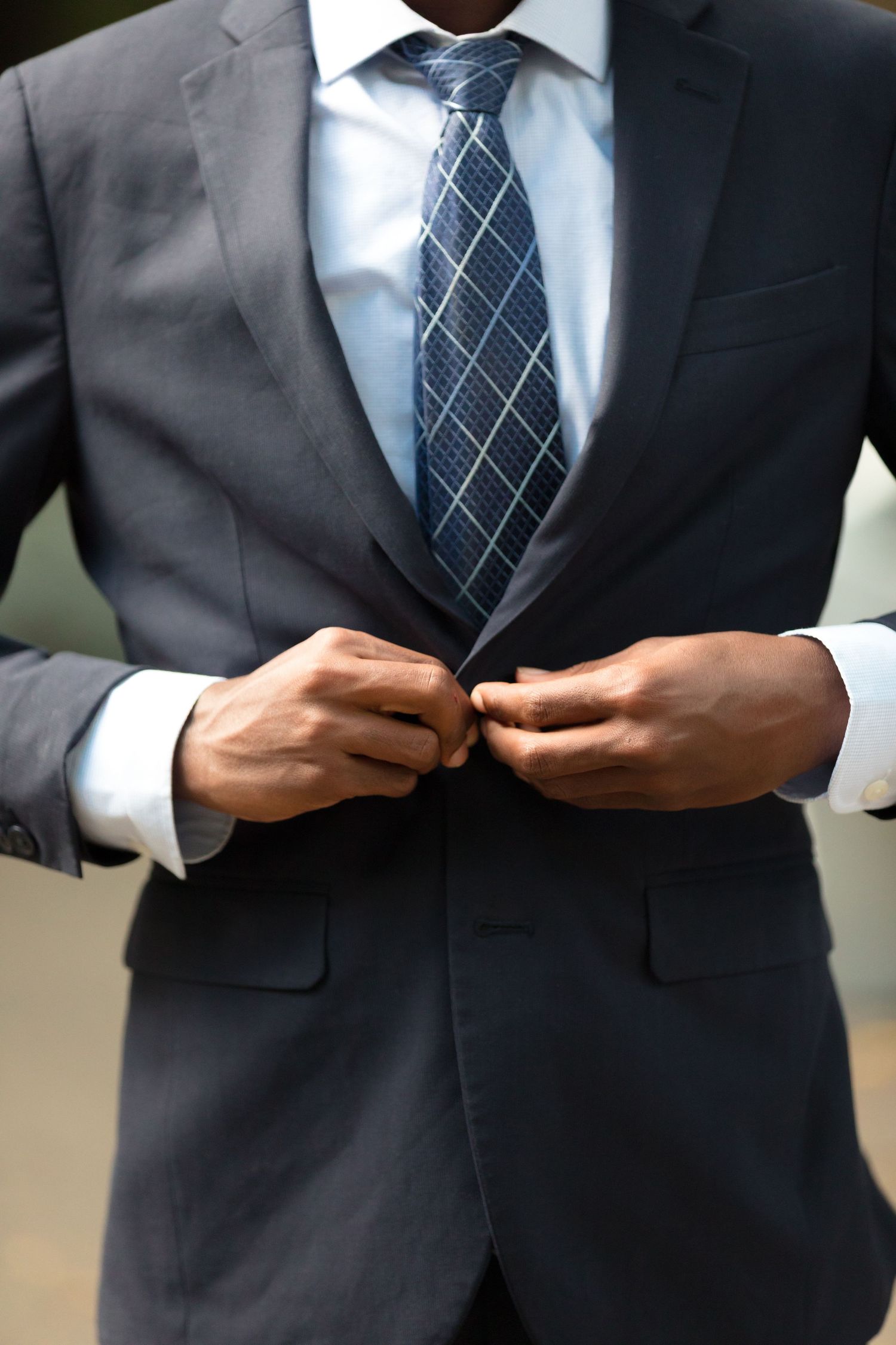 Close-up details of a navy suit and patterned tie during a formal photo shoot.