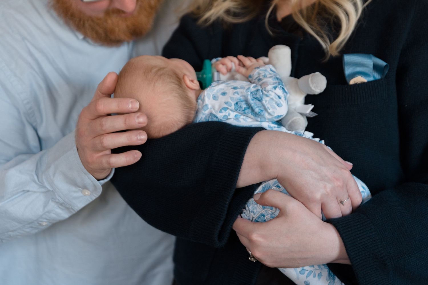Tender family moment with newborn baby wrapped in floral swaddle.