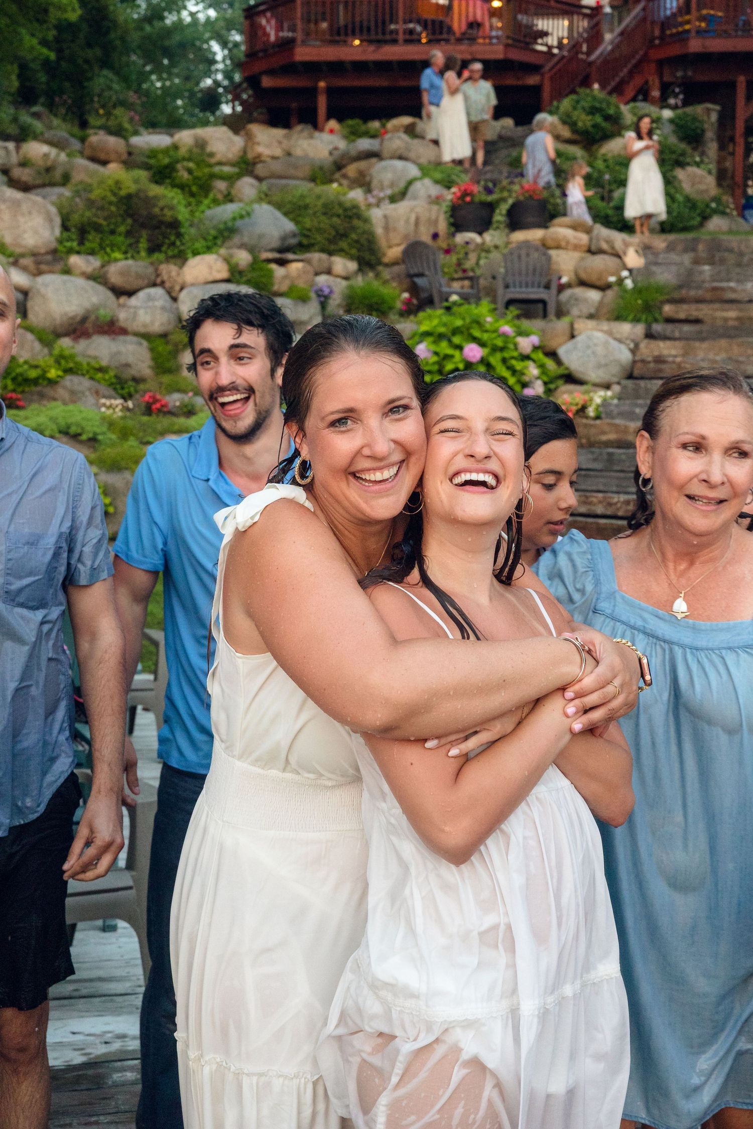 Joyful group embracing in white and blue outfits at outdoor summer gathering.