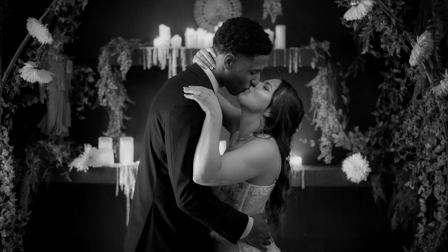 A couple dances together in a dimly lit setting with other dancers visible in the background.
