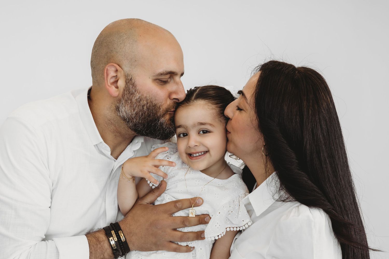 Family of three embracing during a warm studio photoshoot in Dbayeh, Lebanon