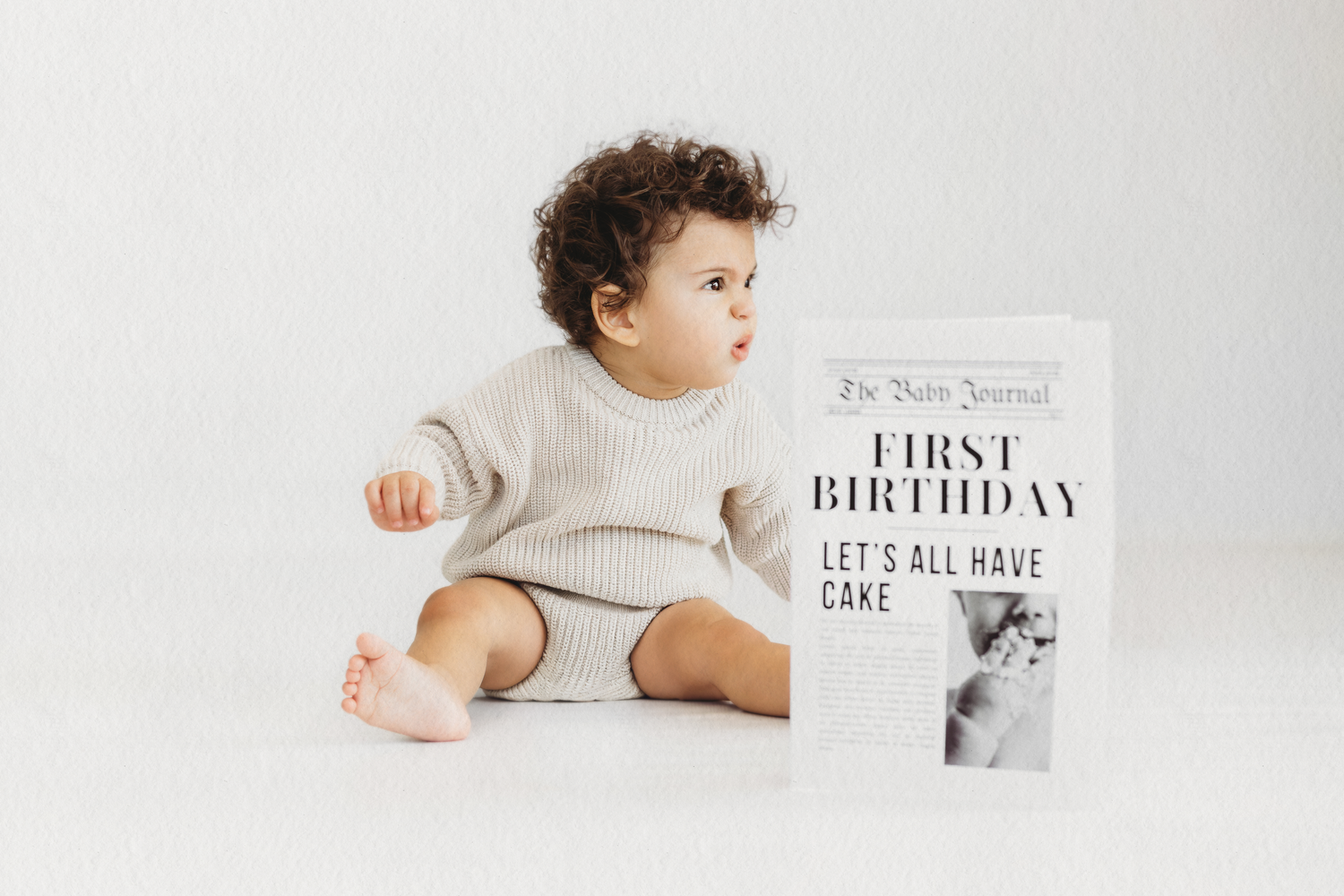 Baby with a first birthday newspaper prop during a cake smash session in Dbayeh, Lebanon