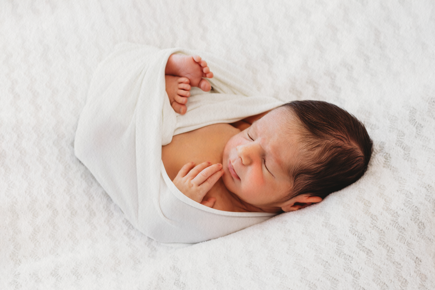 Sleeping newborn baby wrapped in white during a gentle newborn photoshoot in Dbayeh, Lebanon