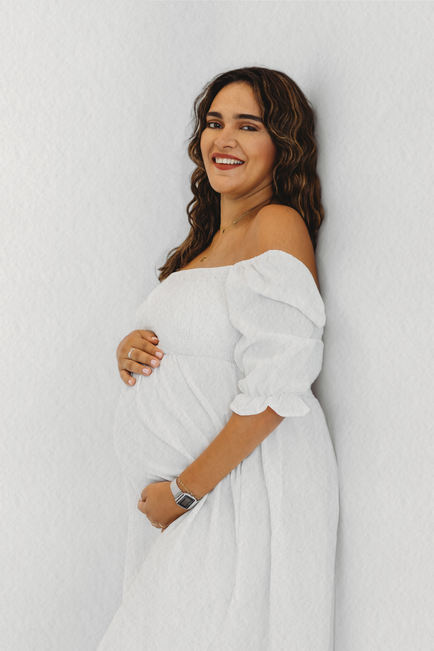 Elegant maternity portrait in a white dress, captured by Dounia Raphael Photography