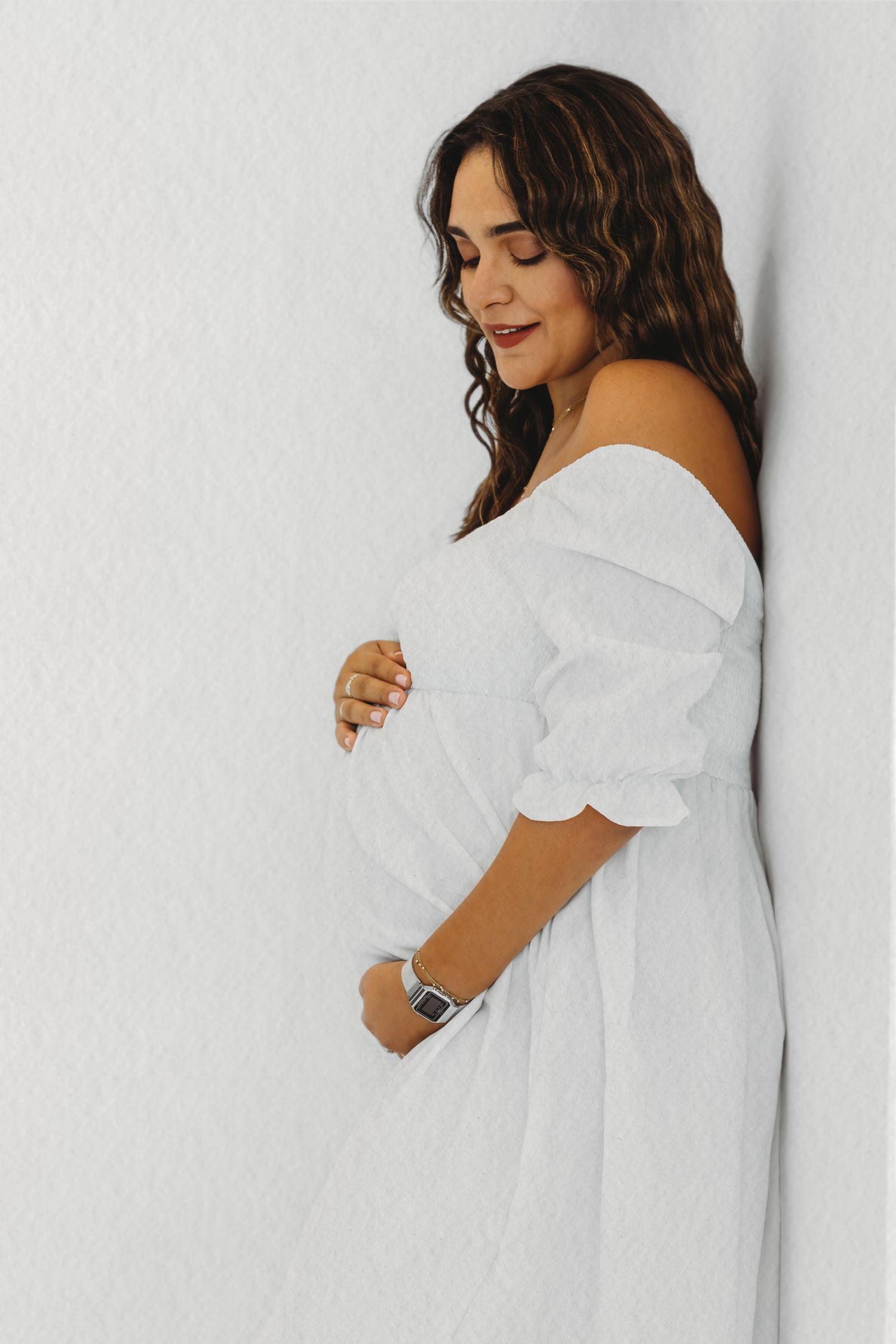 Mother-to-be in a white dress during a gentle maternity photoshoot by Dounia Raphael