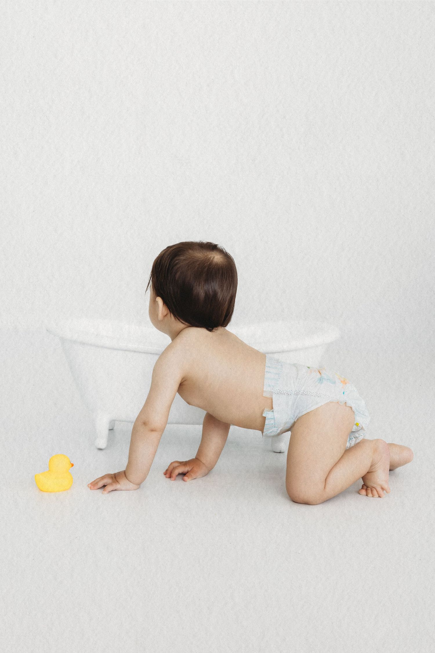 Smiling baby in a vintage bathtub during a bubble bath session by Dounia Raphael Photography
