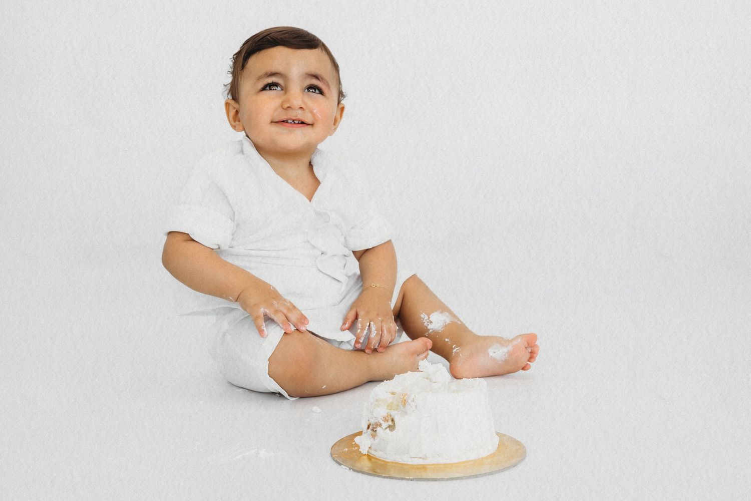 Baby sitting in a white outfit during a baby photoshoot by Dounia Raphael Photography