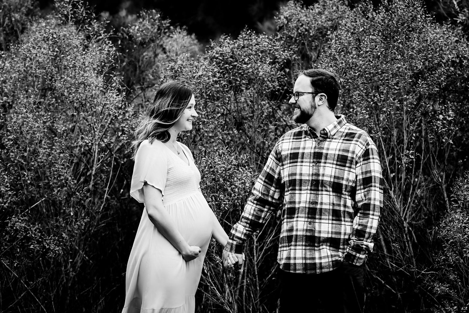 Fine art inspired maternity portrait of couple standing in front of textured bushes during a Lexington SC outdoor maternity portrait session
