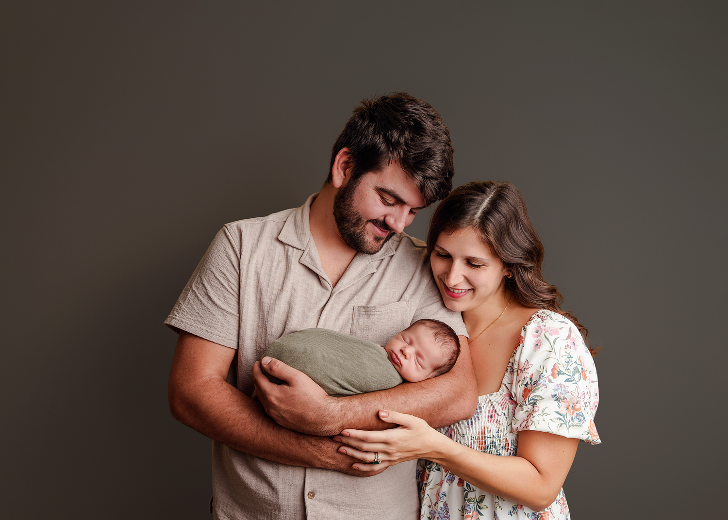 Mom and Dad cuddled in close and gazing lovingly down at their newborn during a studio newborn session for parents from Columbia SC.