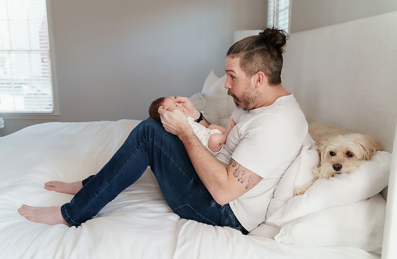 Dad playing peek a boo with his baby girl as the family dog cuddles up against them too during a Columbia SC In-Home Newborn Session.