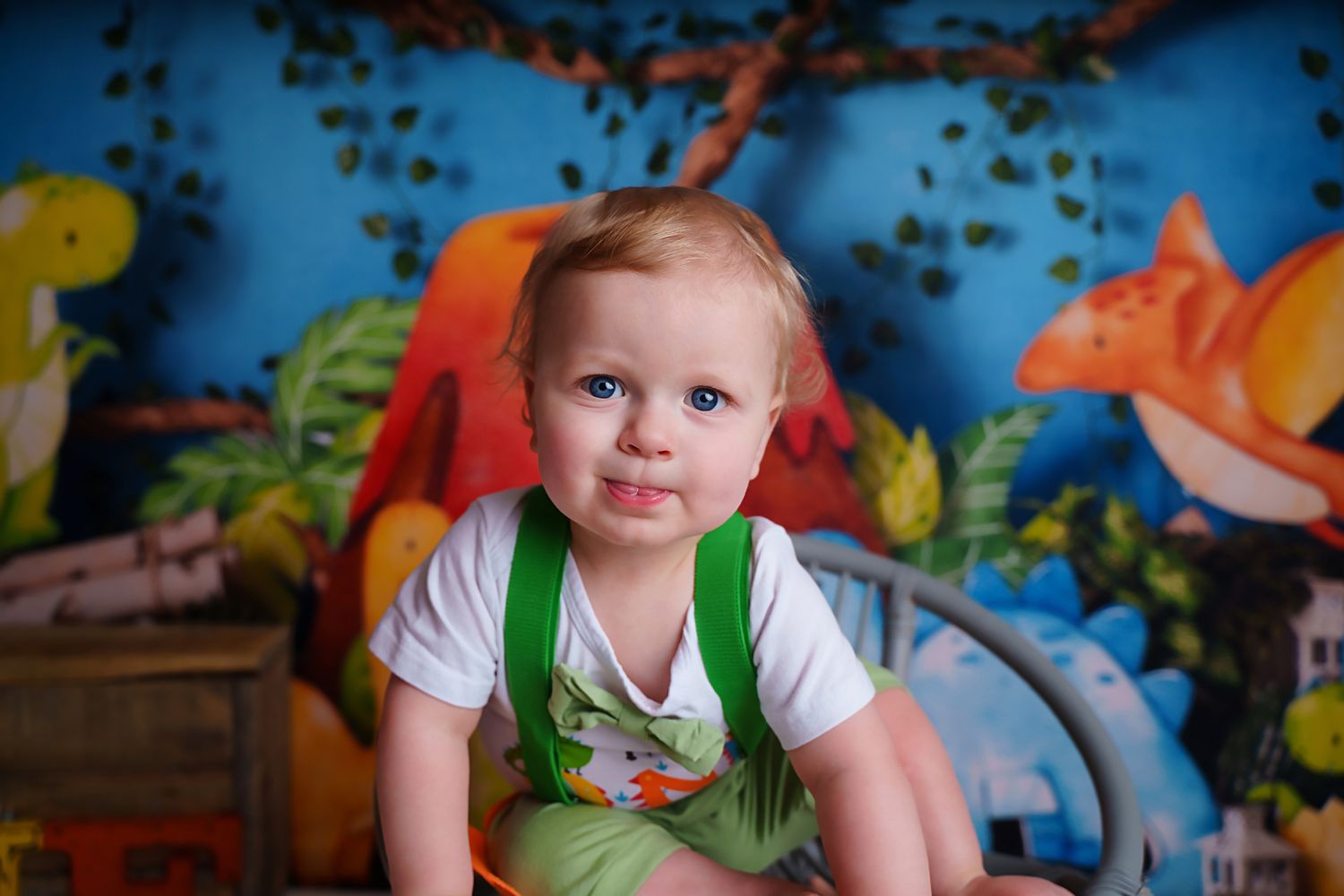 Adorable 1 year old boy from Columbia SC grinning at the camera during his dinosaur themed studio 1st birthday cake smash session.