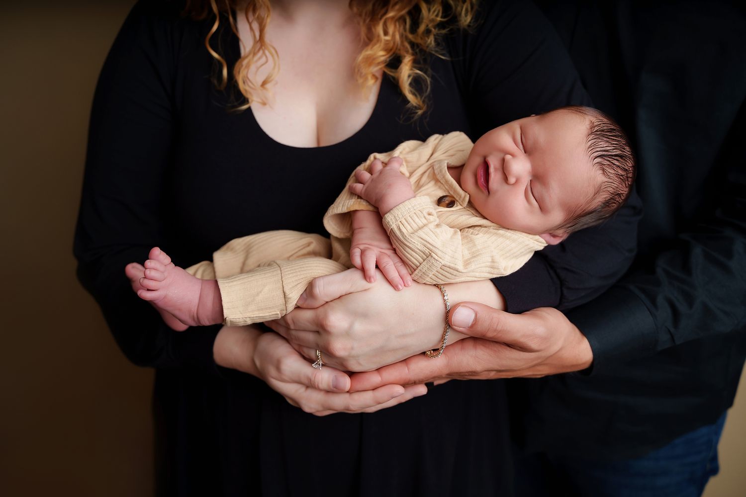 Close-up image of a baby smiling while being held in Mom and Dads arms during a Lexington SC Studio Newborn Portrait Session.