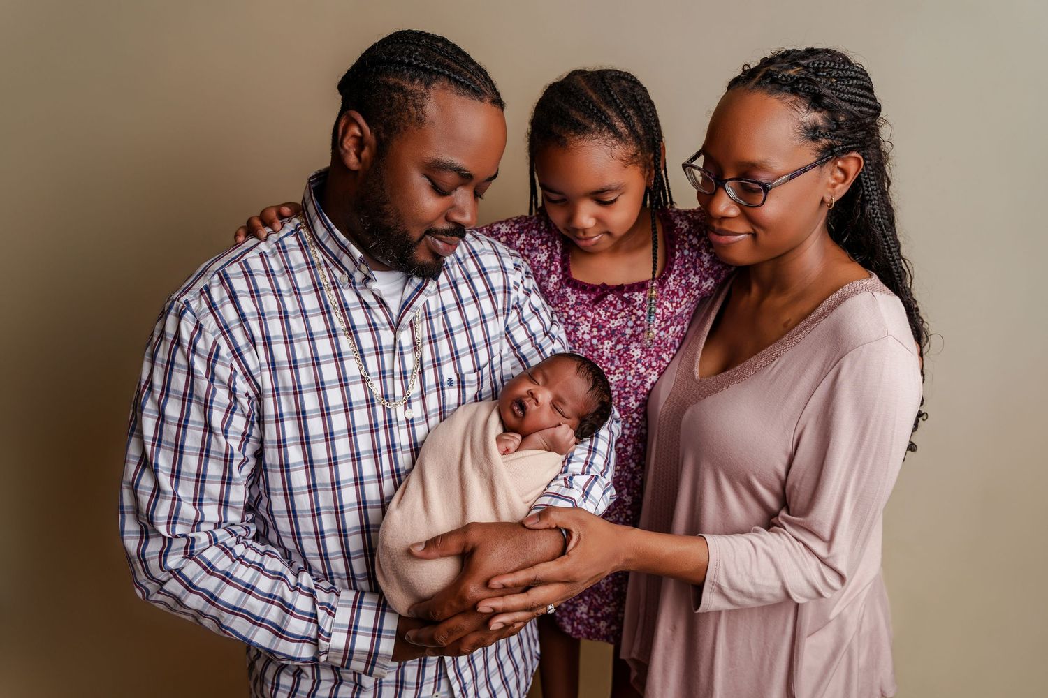 Dad holding his newborn baby girl as his older daughter and wife are cuddled in close during a Chapin SC Studio Newborn Portrait Session.