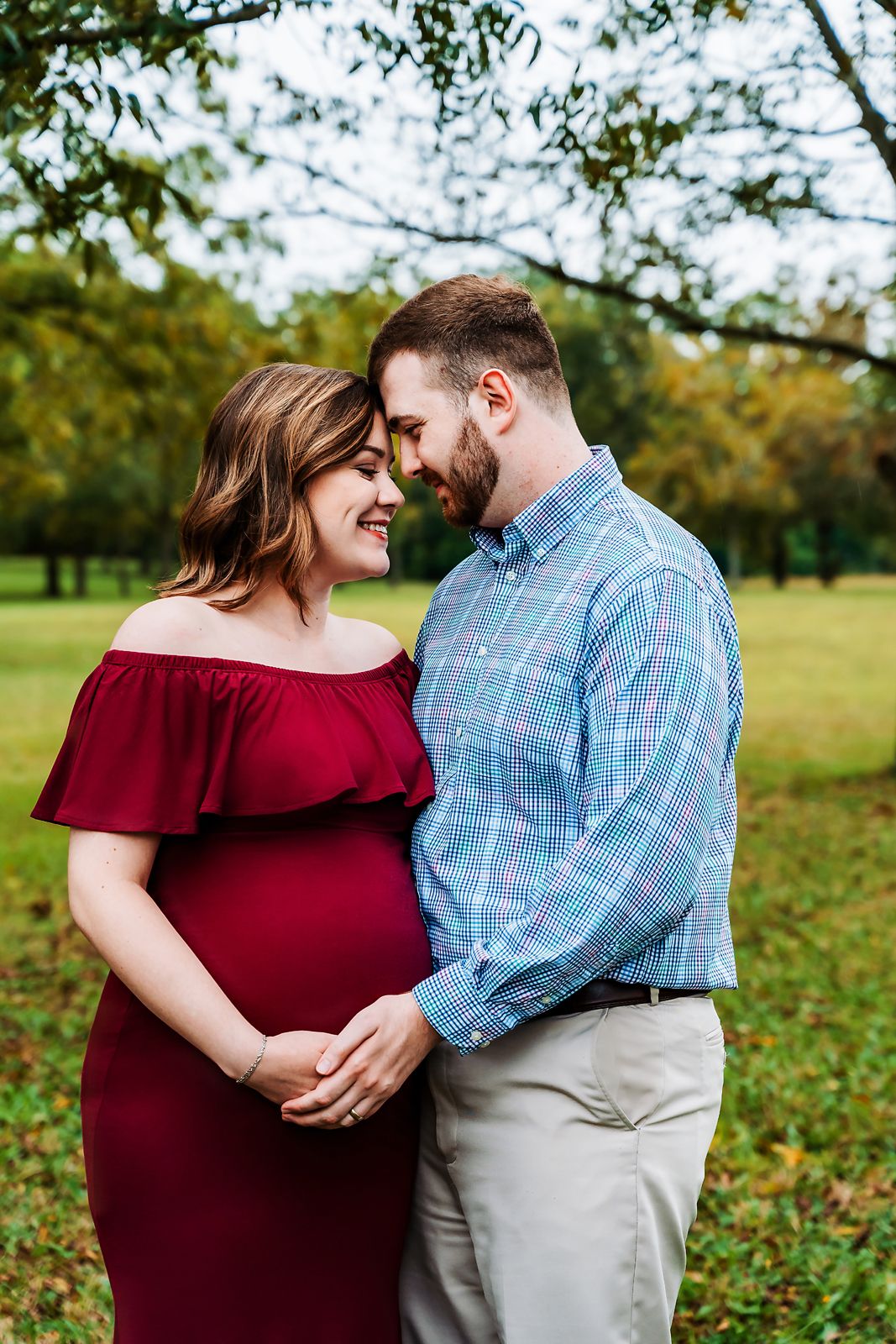 Close-up maternity portrait of a couple in a field with pecan trees in the background during a Lexington SC Maternity Session.