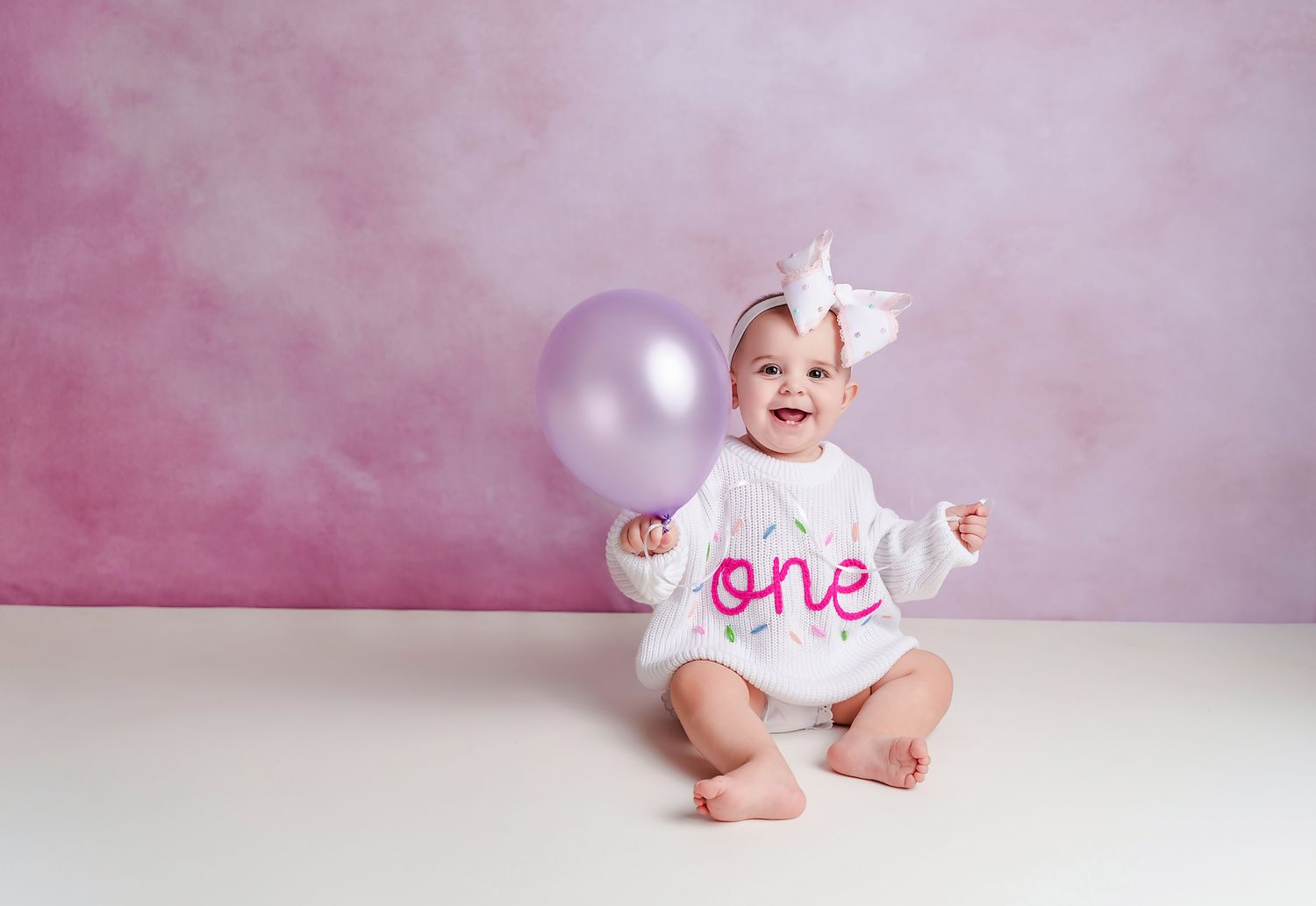 Simple 1st birthday portrait of a little girl in a ONE sweater and holding a balloon during a Studio Session for a client from Newberry SC.