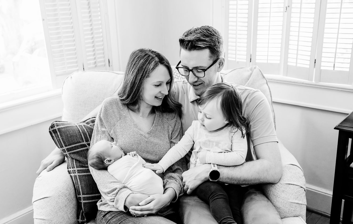 Mom, Dad, toddler and newborn all cuddled up together and lovingly interacting during a Columbia SC in-home newborn photography session.