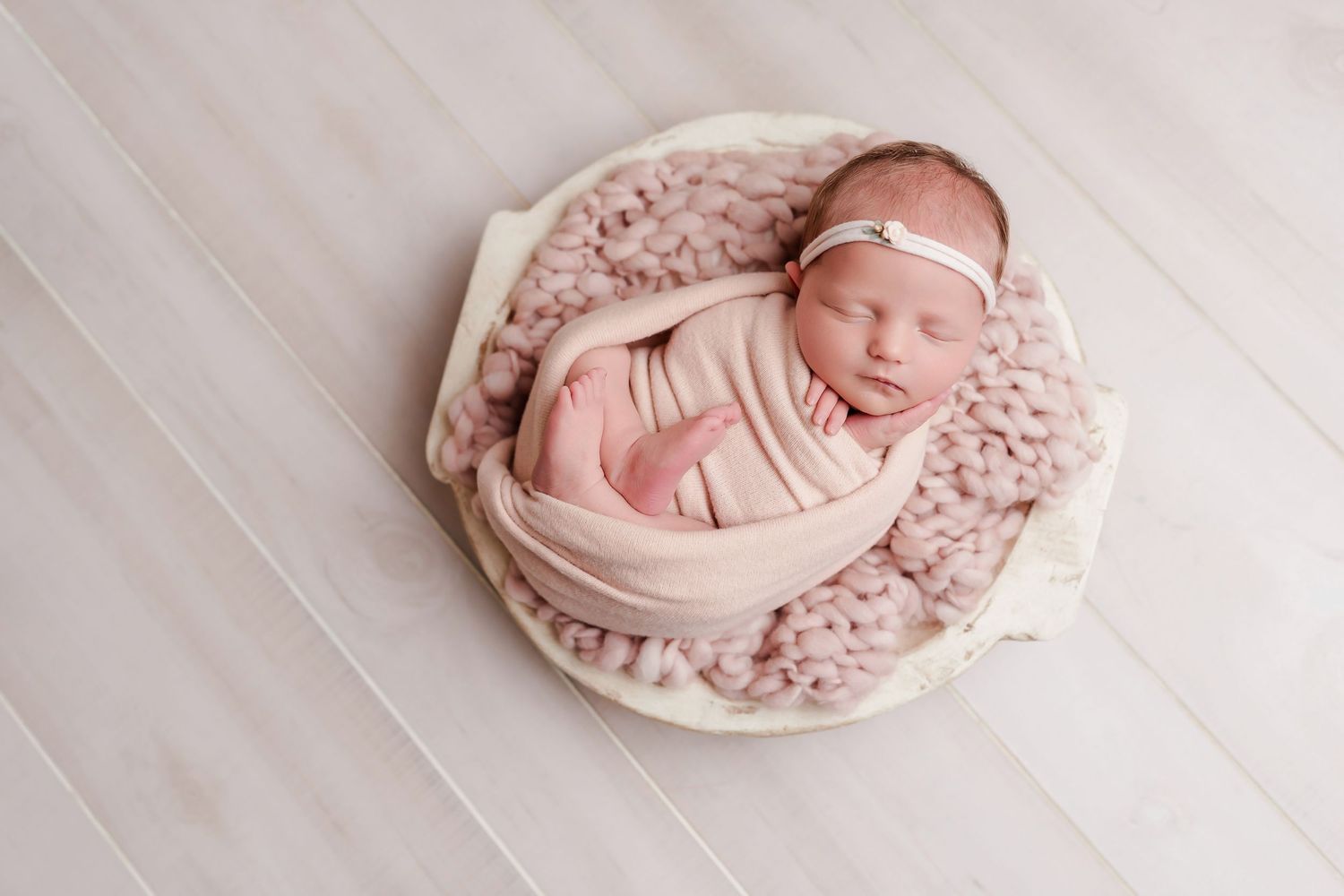 Baby swaddled so that her toes are visible and posed in a prop on a pink toned blanket during a Lexington SC Studio Newborn Session.