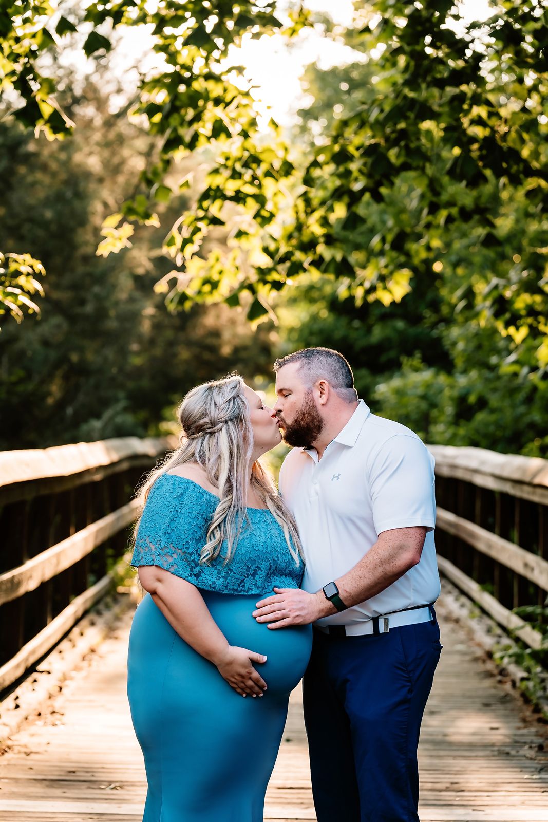 Maternity Portrait of a couple on sunlight dappled wooden bridge with glowing leaves framing them during a Newberry County Maternity Session