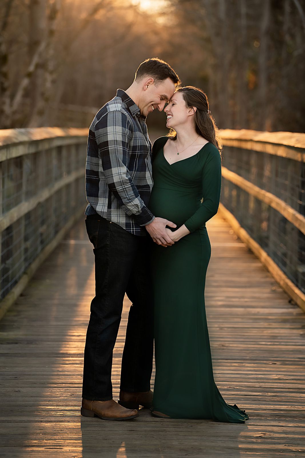 Sunset maternity portrait of a couple posing on a wooden bridge with golden light illuminating behind them during a Chapin SC Session.