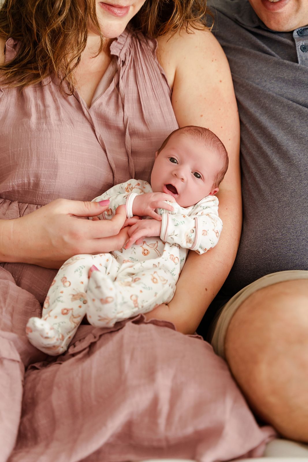 Close-up of a newborn baby girl looking at the camera while in Mom and Dad's arms during an Irmo SC In-Home Newborn Portrait Session.