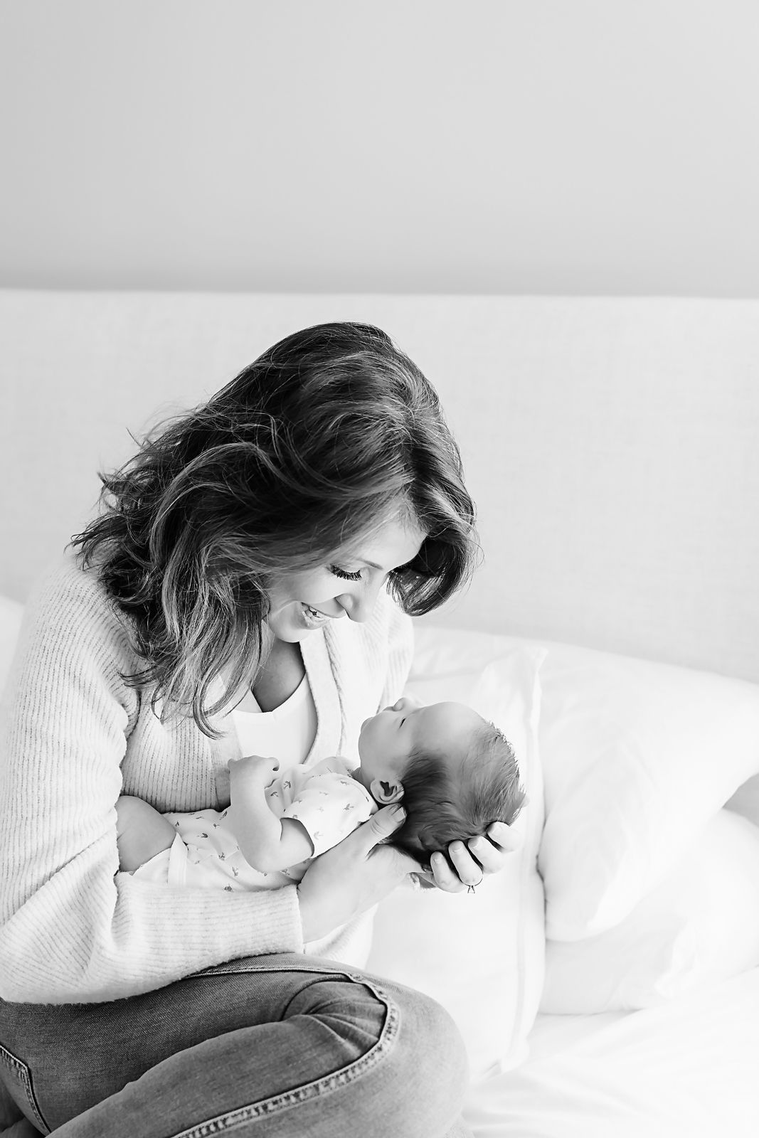 Mom lovingly looking down at her newborn baby girl during a Columbia SC lifestyle in-home newborn portrait session.