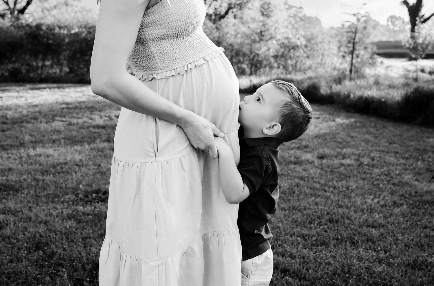 Black and White image of a young boy kissing his Moms Belly during a Columbia SC Maternity Portrait Session.