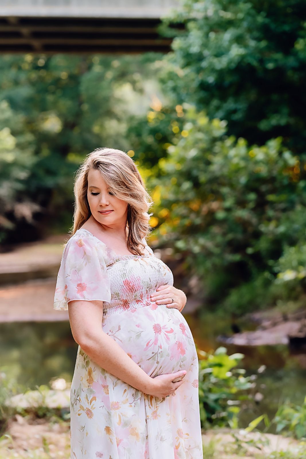 Stunning Mama To Be standing in front of a creek during a Chapin SC Maternity Session.