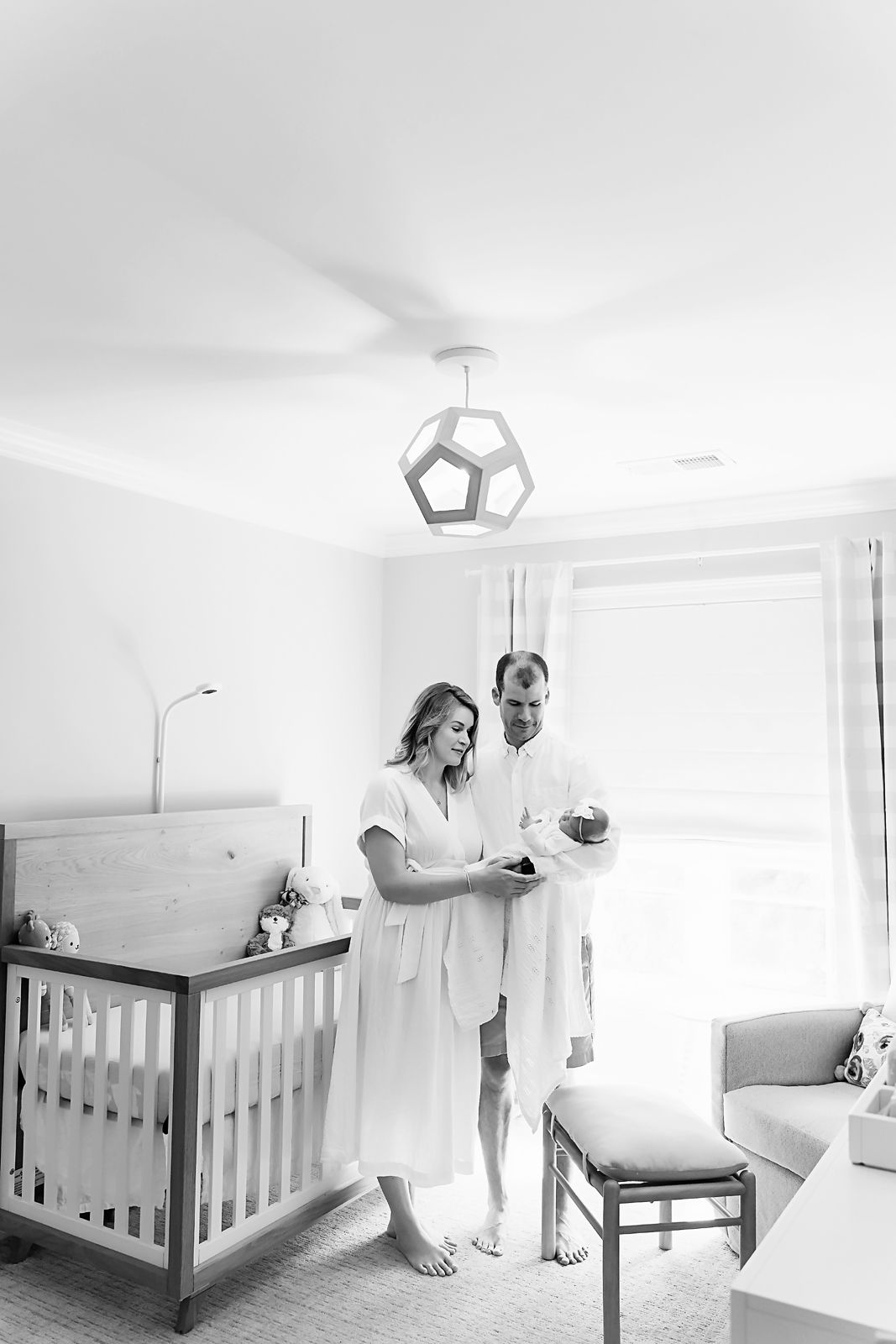 Mom and Dad standing in their babies nursery and embracing their newborn during a Lexington SC Newborn Portrait Session.