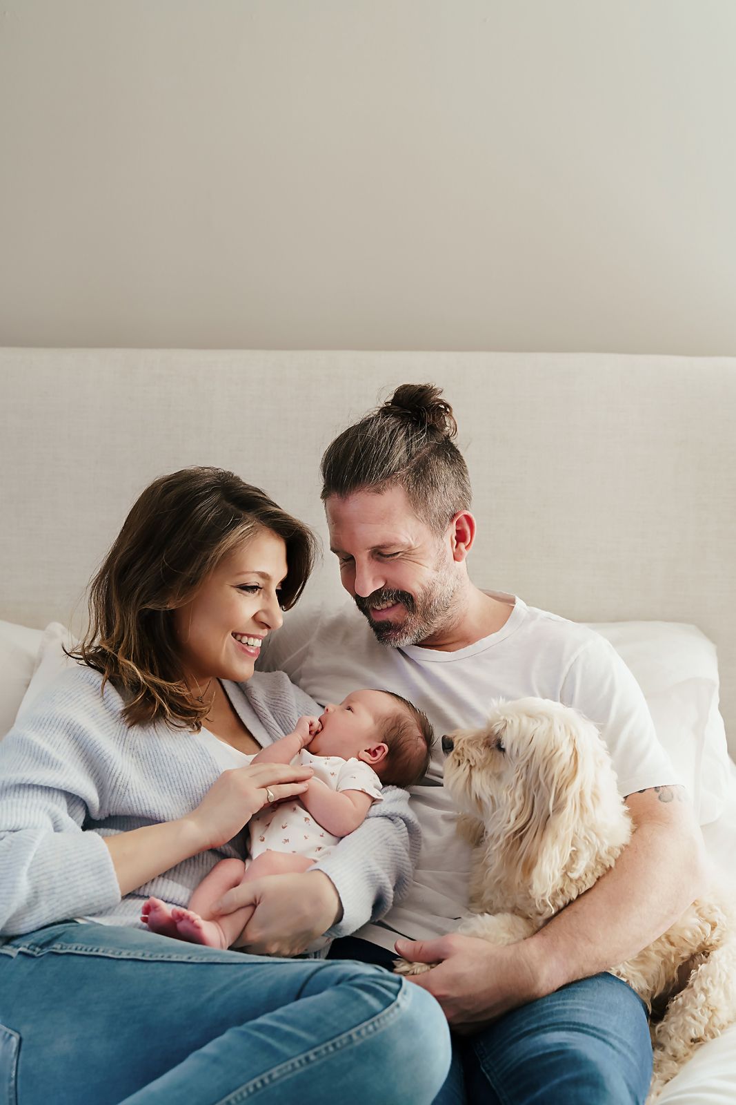 Sweet image of Mom and Dad cuddling their newborn baby as their small dog also cuddles up to them during a Columbia SC Newborn Session.