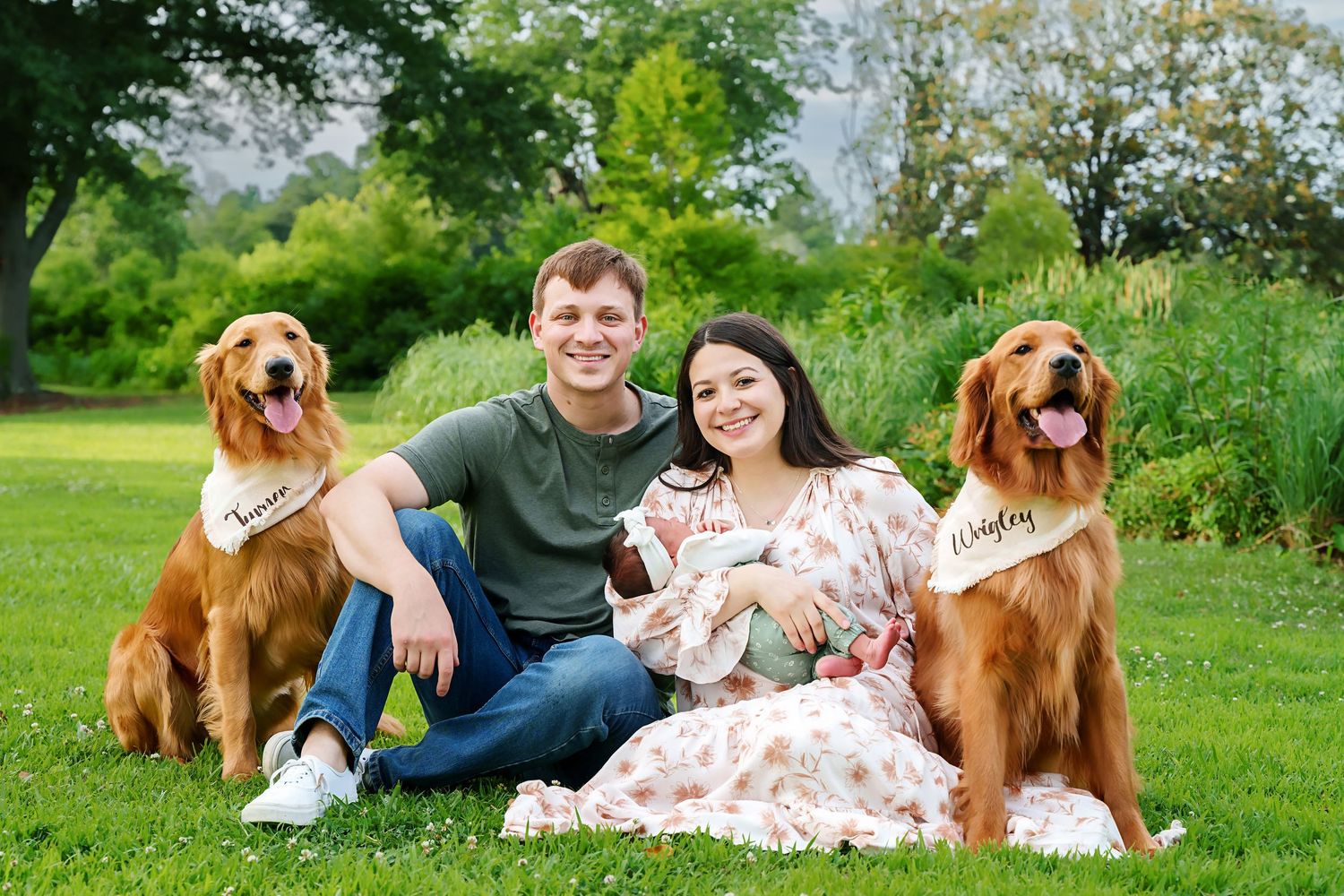 Mom and Dad embracing their new baby while also posing with their two dogs during an outdoor newborn family portrait in Columbia SC.