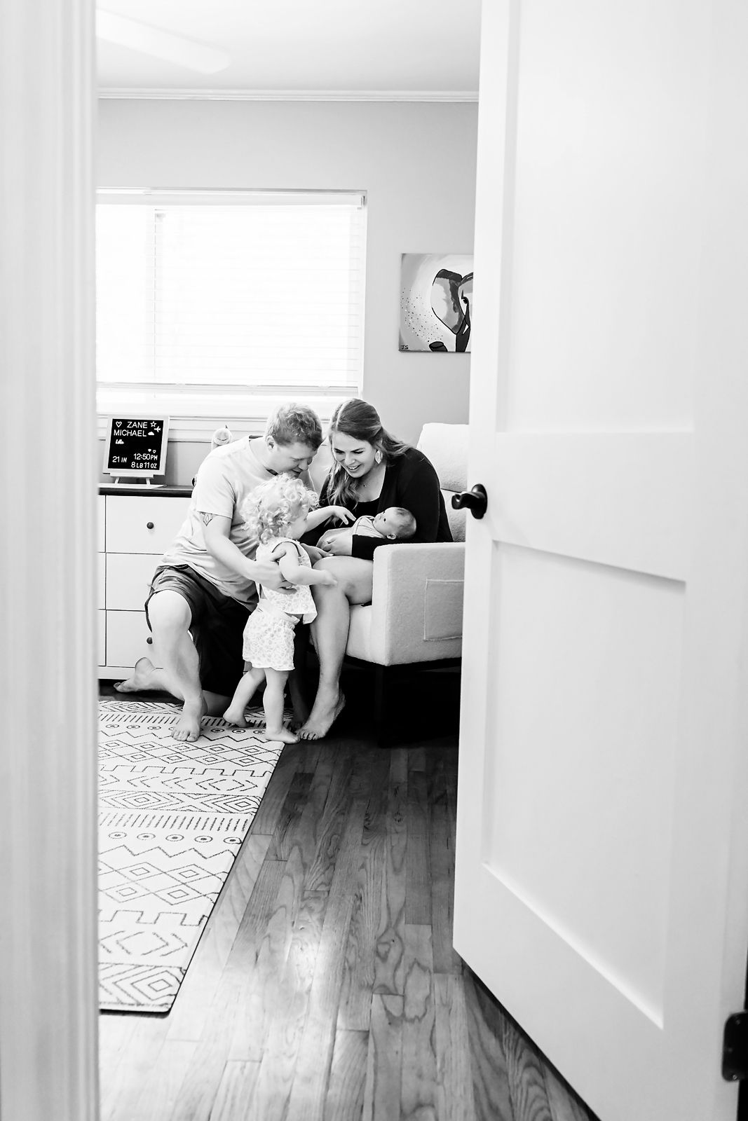 Storytelling image looking through the doorway to capture a new family welcoming their newborn during a Columbia SC in-home newborn session.