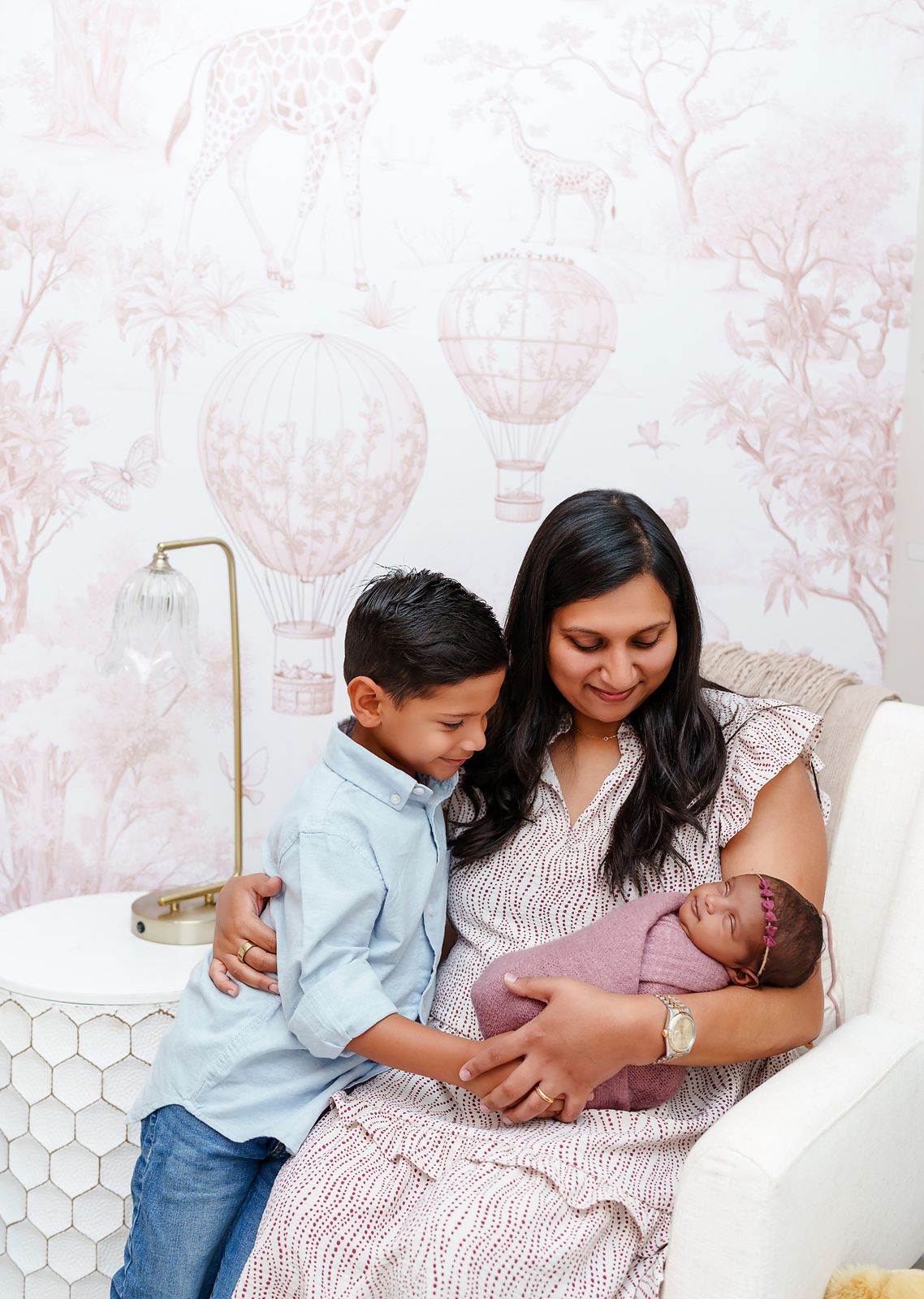 Mom holding her smiling newborn while her older son leans in during a Lexington South Carolina lifestyle in-home newborn portrait session.