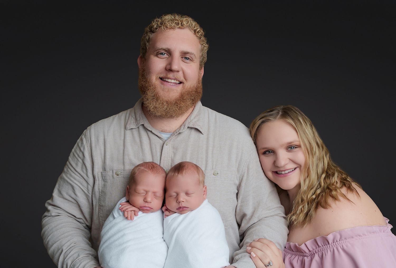 Dad holding their newborn twins while mom lovingly leans in during a Studio Newborn Session for clients from Lexington SC.