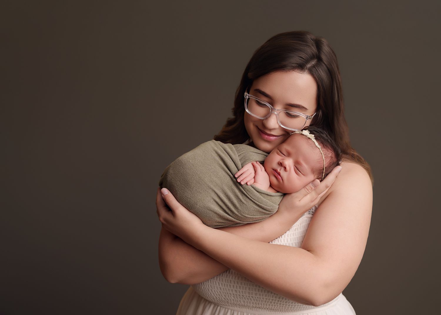 Chapin SC studio newborn photography image of mom cuddling her newborn close while smiling softly, against a dark backdrop.