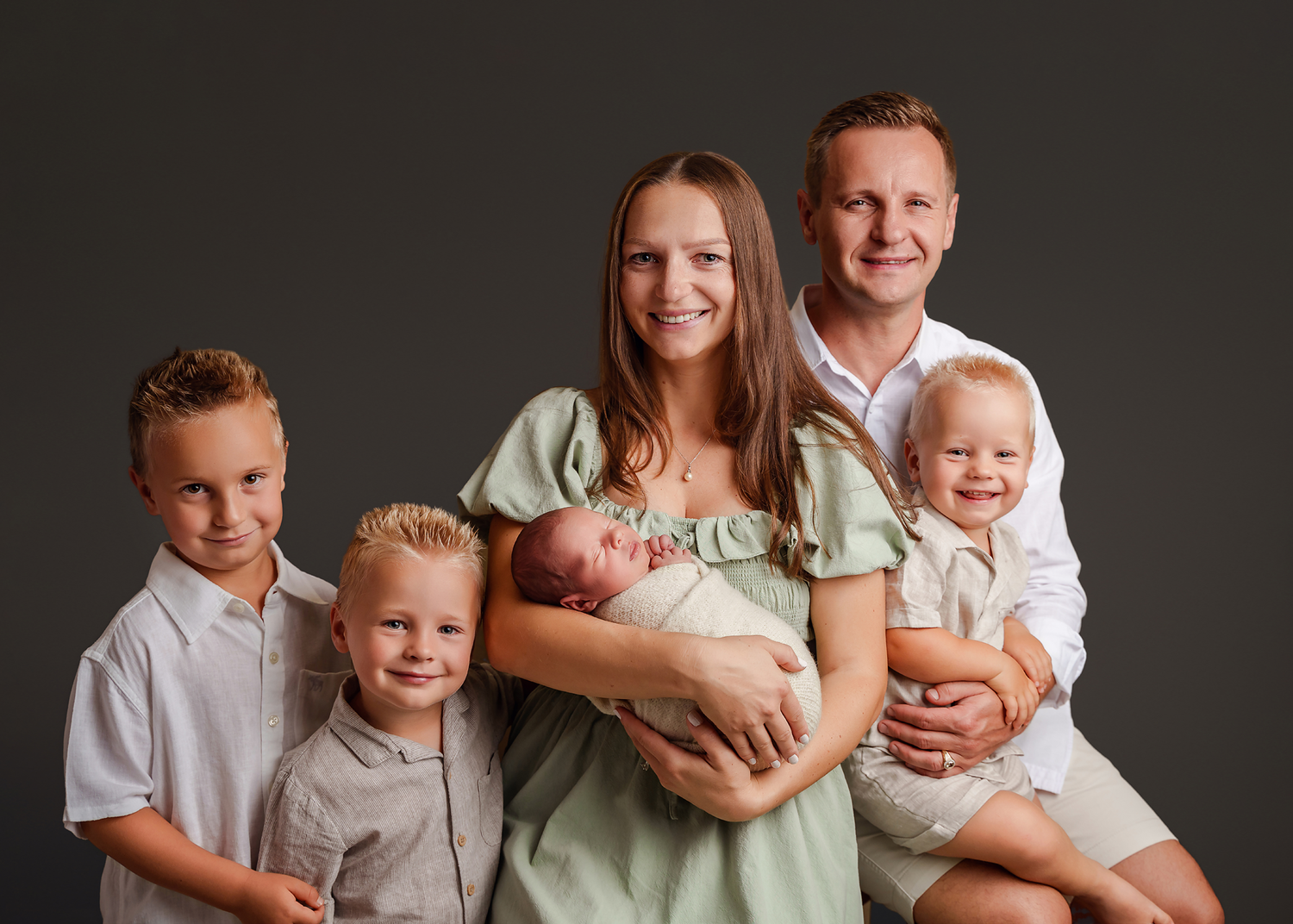 Mom and Dad from the upstate of SC posing with all 4 of their children including their newborn during a Studio Newborn Session in Chapin SC.