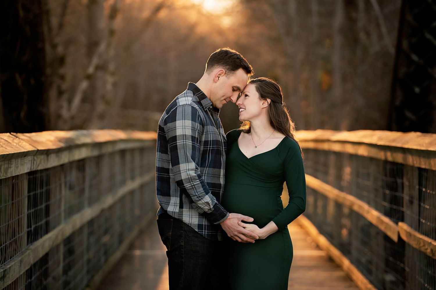 Stunning backlit winter time maternity portrait of a couple embracing on a bridge at the Palmetto Trail in Peak South Carolina.