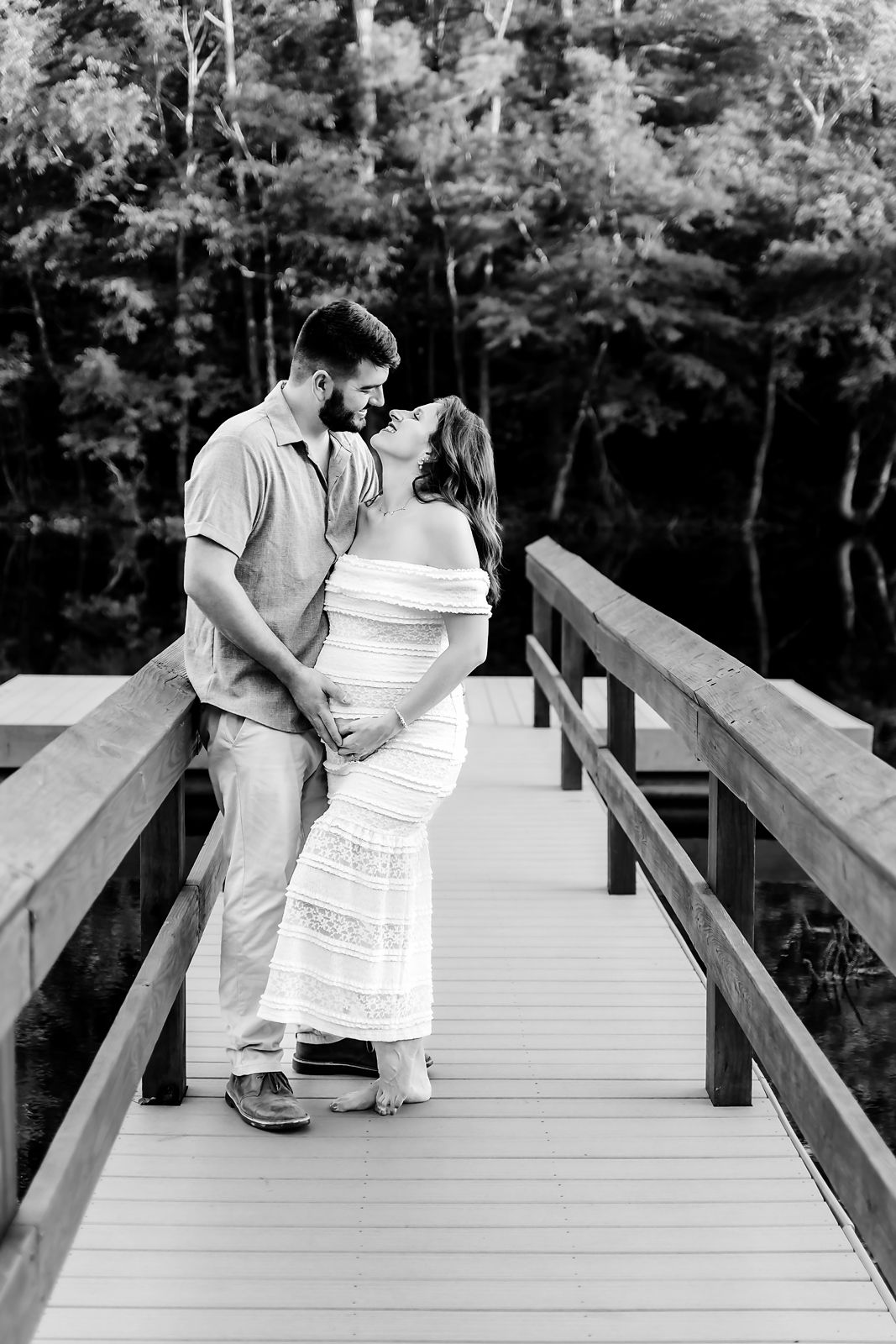 Mom and Dad to be posing together on a dock and looking at each other during a Lexington SC outdoor Maternity Portrait Session.