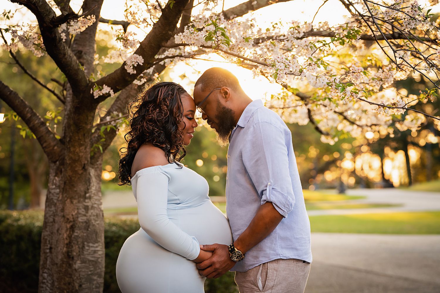 Beautiful maternity portrait of a couple beneath a blooming dogwood tree with sunset lighting during a Columbia SC Maternity Session.