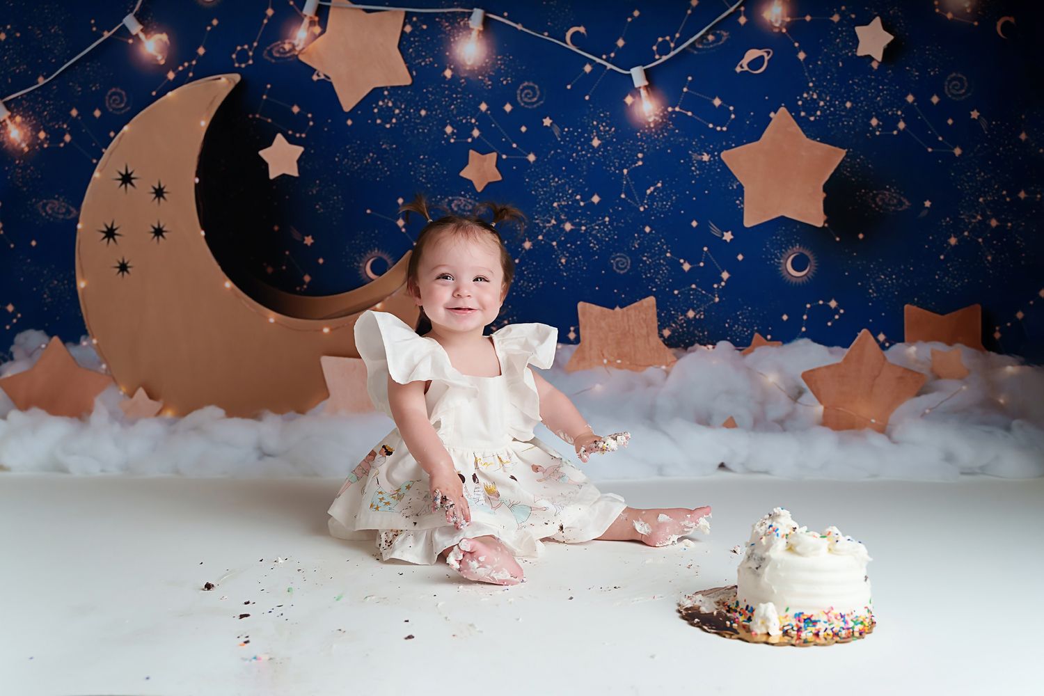 Adorable little girl smiling at the camera during her celestial themed dark blue and gold Lexington SC 1st Birthday Cake Smash Session.
