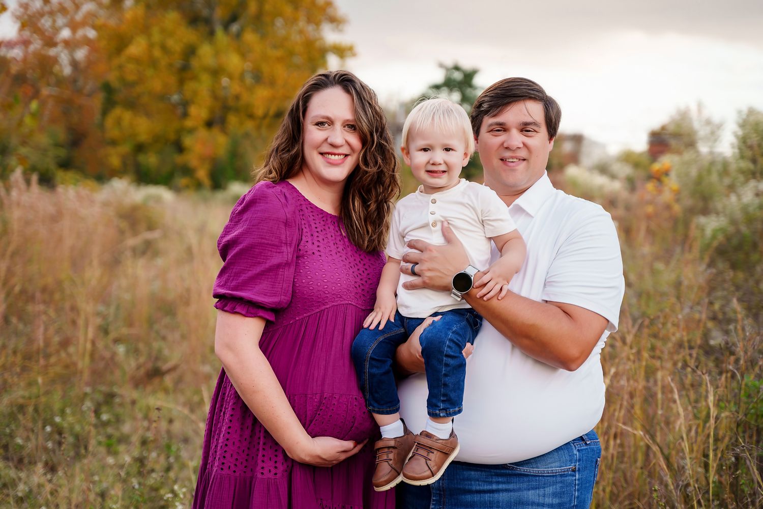 Dad holding his toddler son while mom cradles her belly during a field maternity portrait session in Columbia SC.