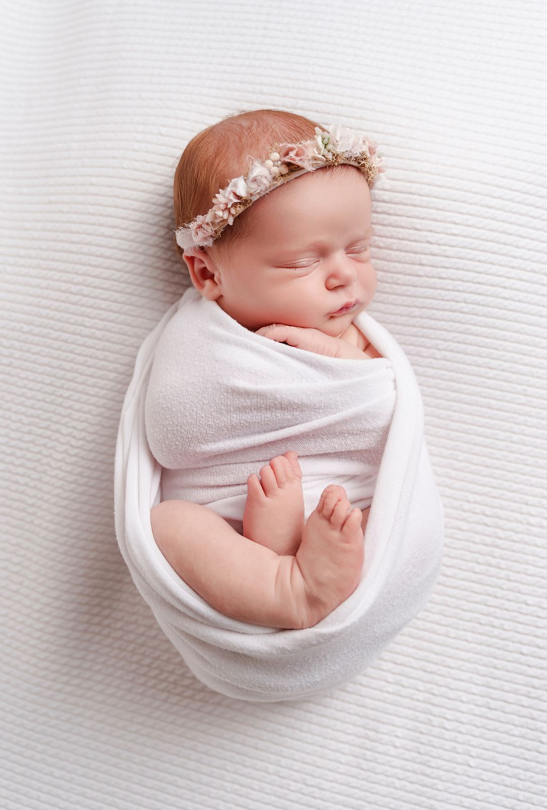 Timeless studio newborn portrait of baby in a white swaddle that shows her little feet on a white background, for Columbia SC client.
