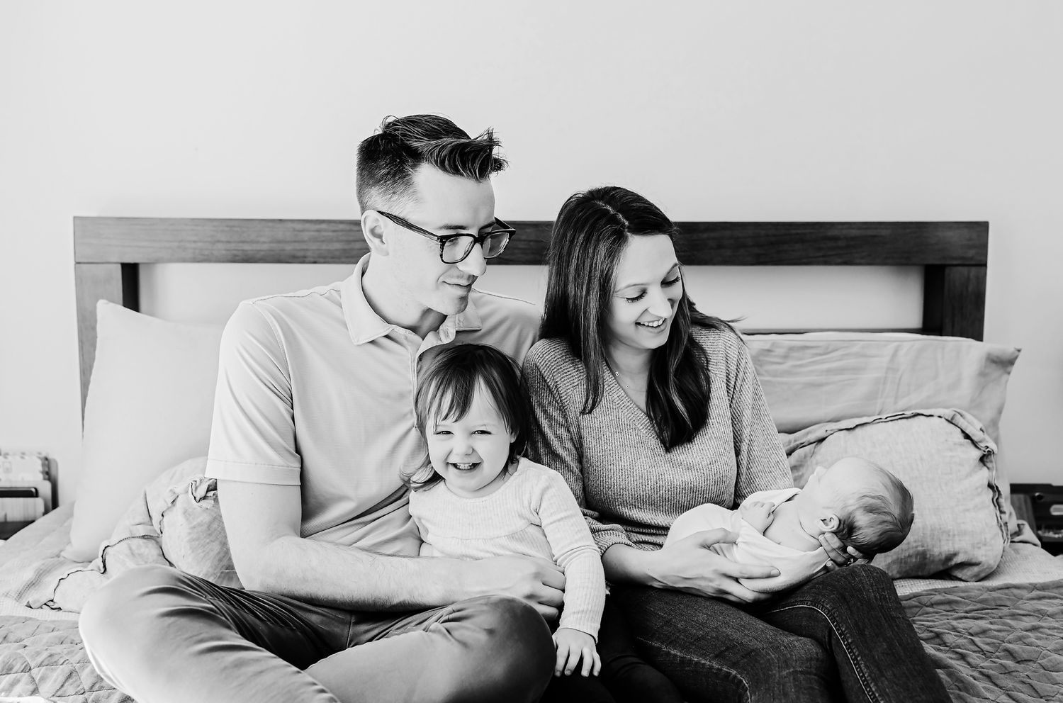 In-home Columbia SC newborn photography session showing parents smiling at their newborn while toddler smiles at the camera.