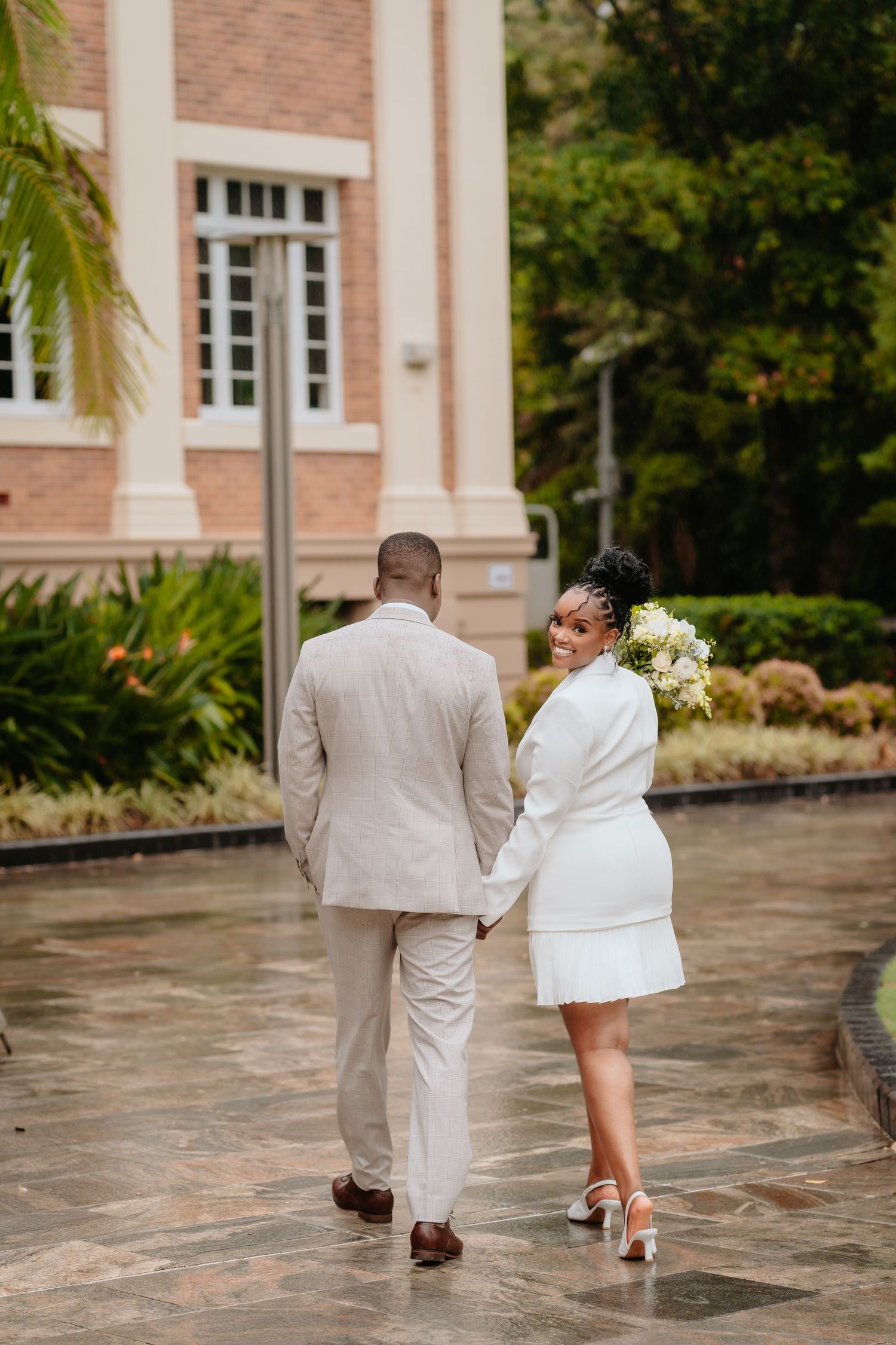 Brisbane wedding photographer — bride and groom walking hand in hand outside a beautiful venue, candid and romantic wedding moment by Joy Fi
